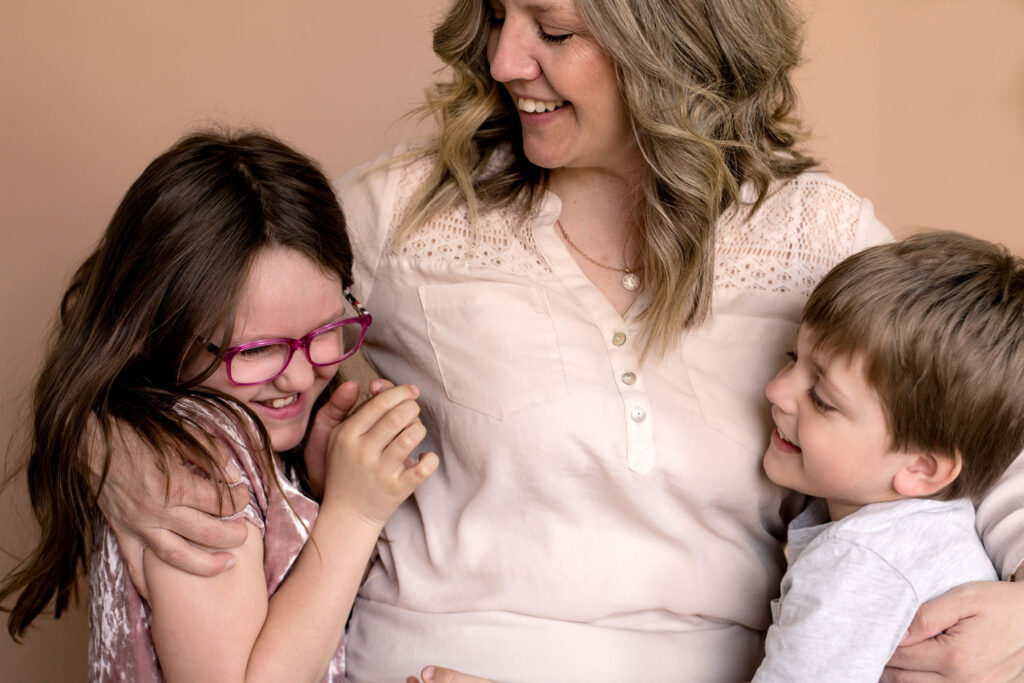 mom hugging daughter and son while they are laughing