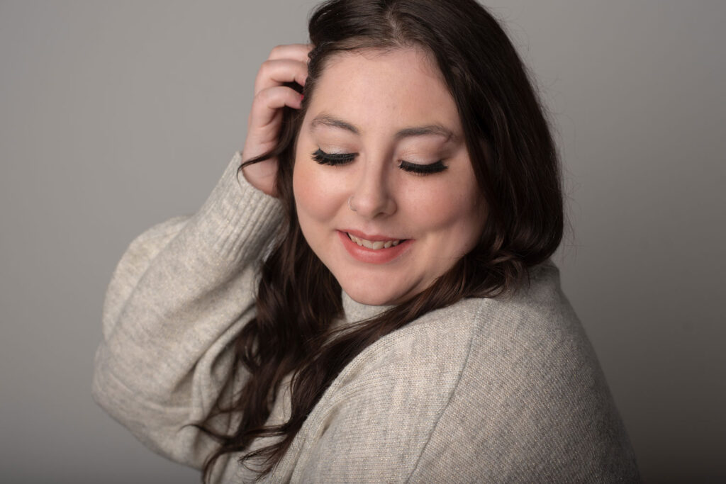 woman looking down her shoulder, tucking hair behind her ear