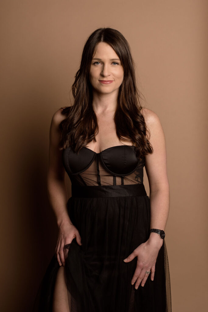 woman in a sheer black corset dress looking straight at camera