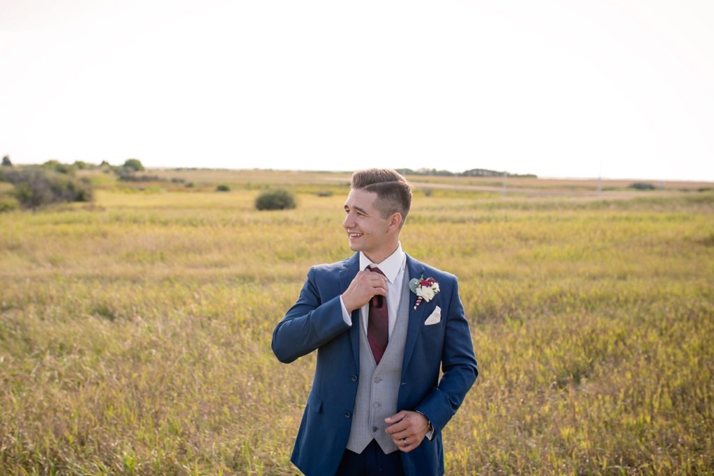 groom adjusting his tie looking off camera