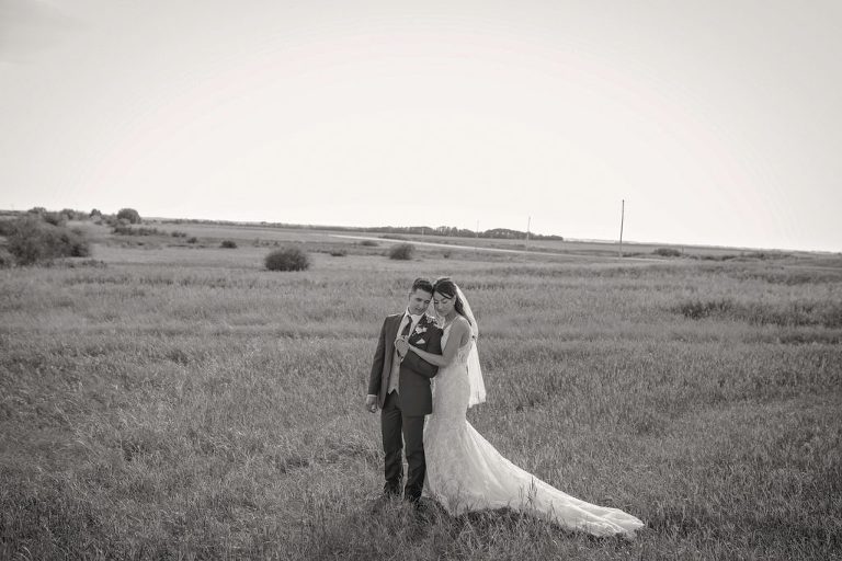 bride and groom cozying up in a empty field
