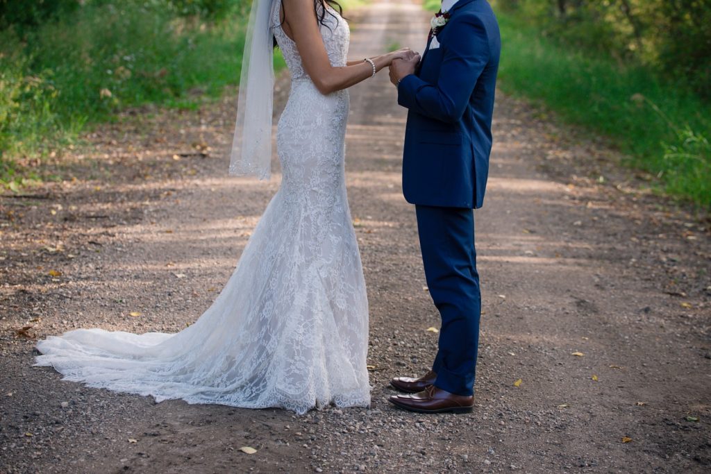 bride and groom holding hands on a a dirt road