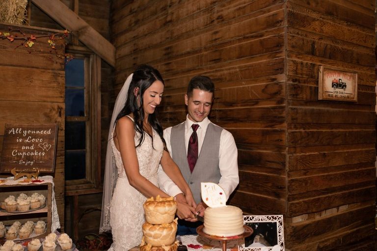 bride and groom cake cutting at reception in rustic barn